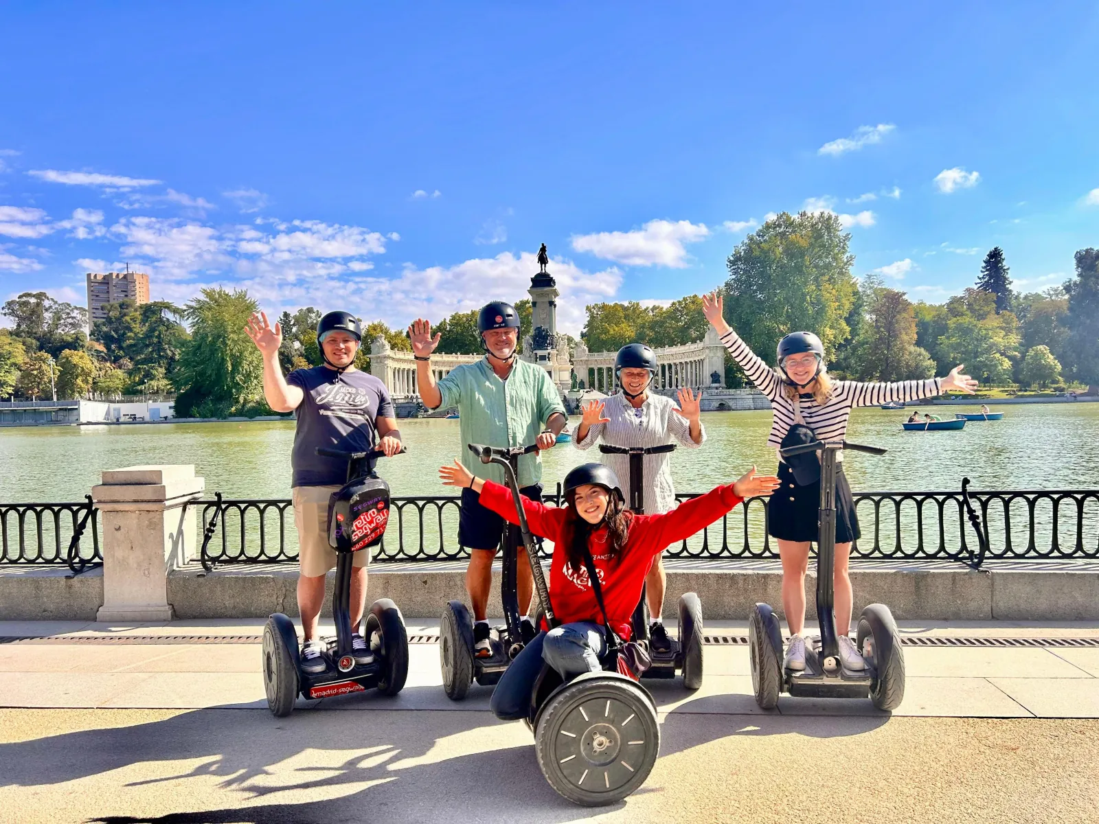 Riders raising their arms on Segways beside the Retiro lake