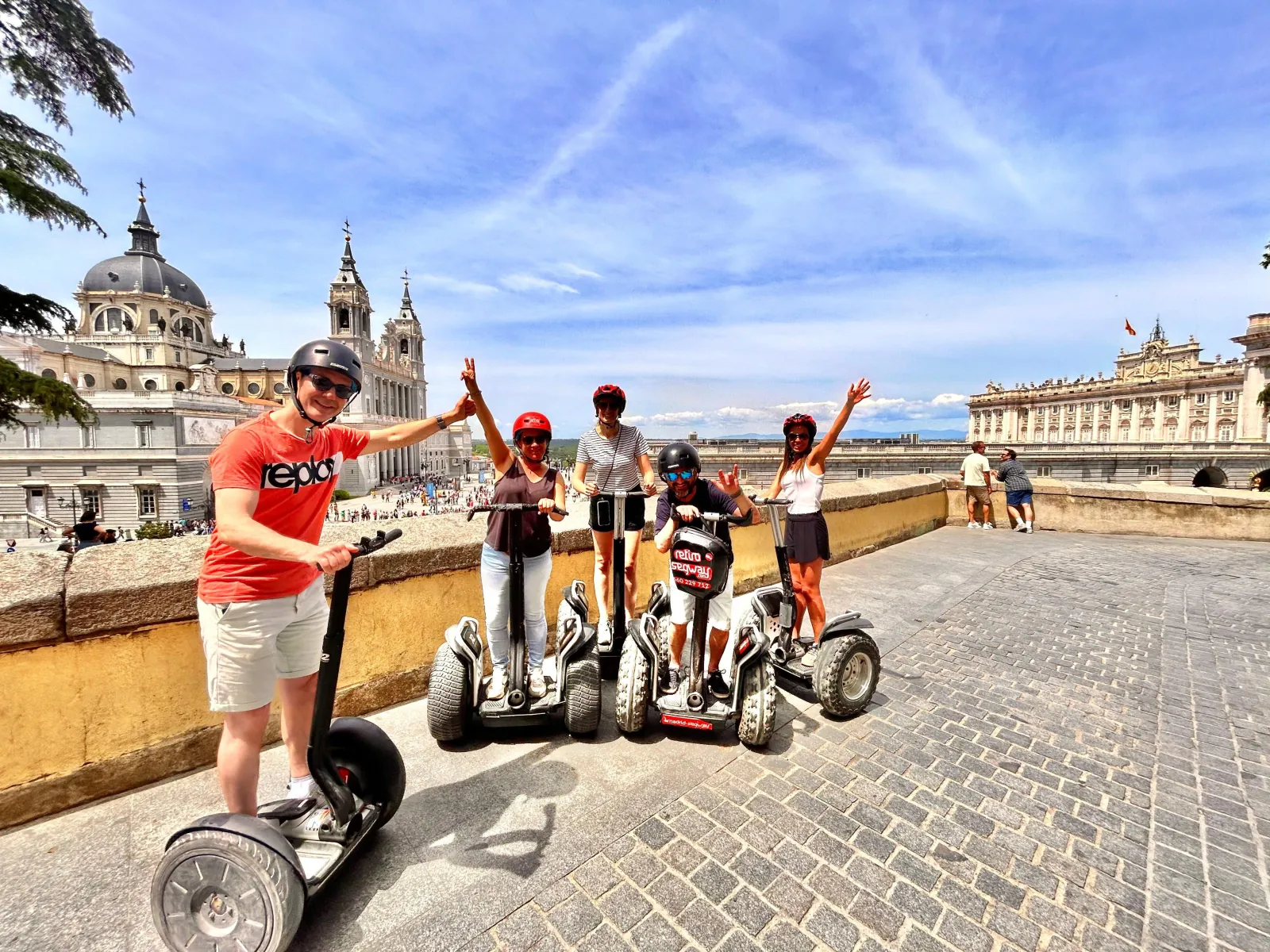 Riders raising their arms on Segways above the Madrid rooftops