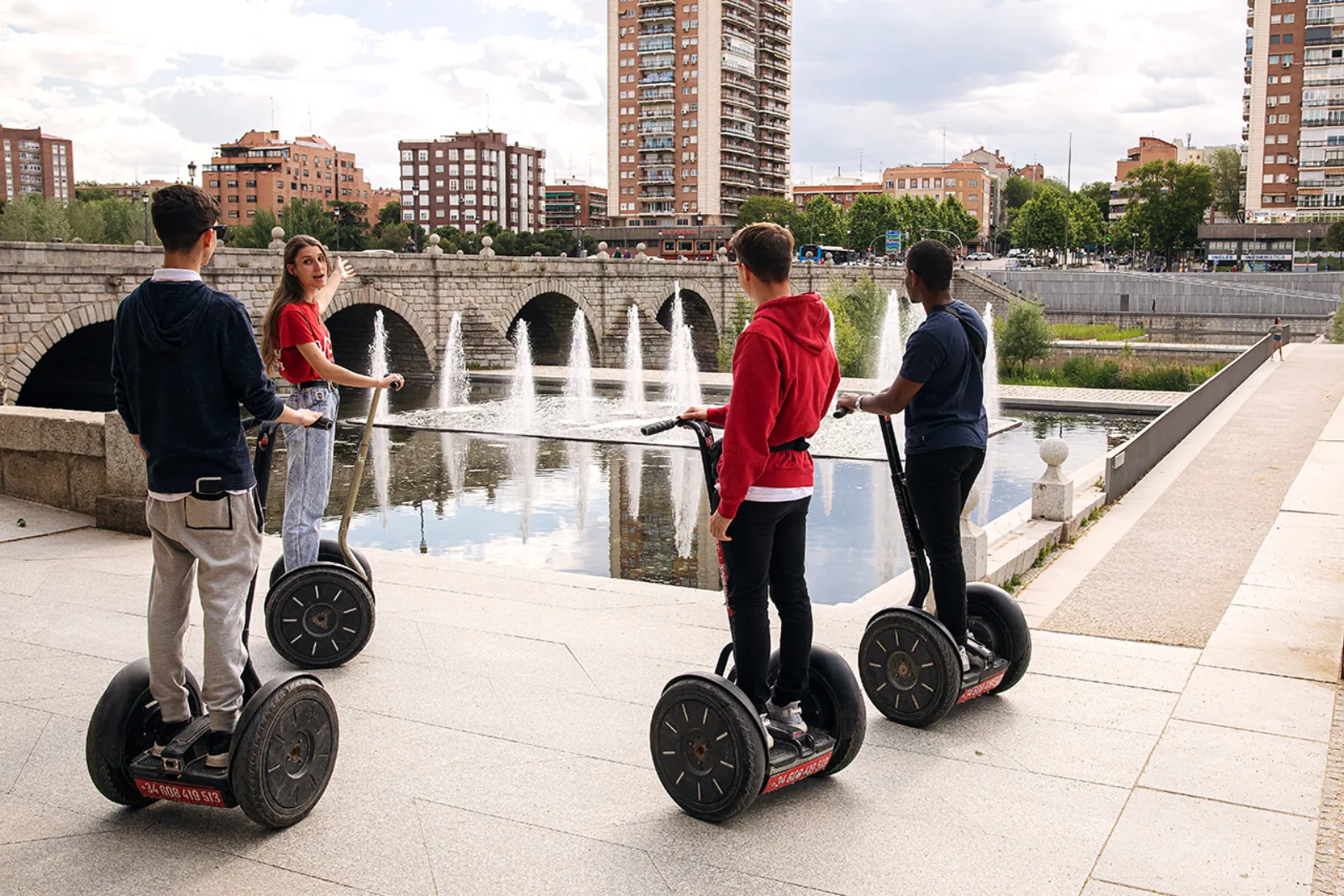 Segway riders beside a stone bridge over the Manzanares
