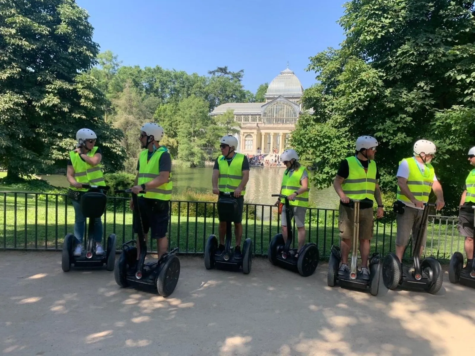 Riders in hi-vis vests on Segways by the Retiro lake