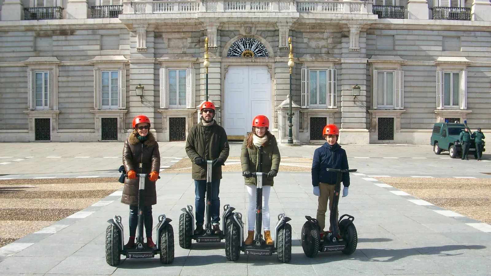 Riders in winter coats on Segways at the Royal Palace gate