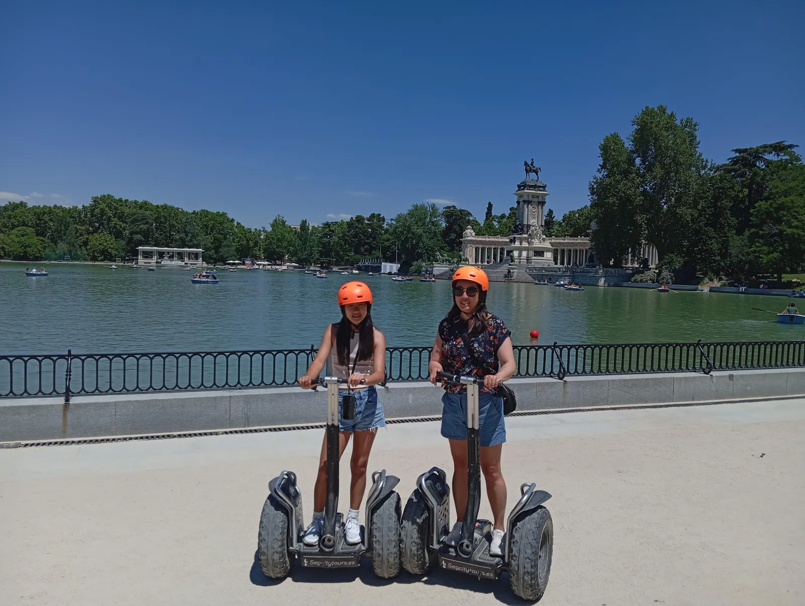 Two riders on Segways at the edge of the Retiro lake
