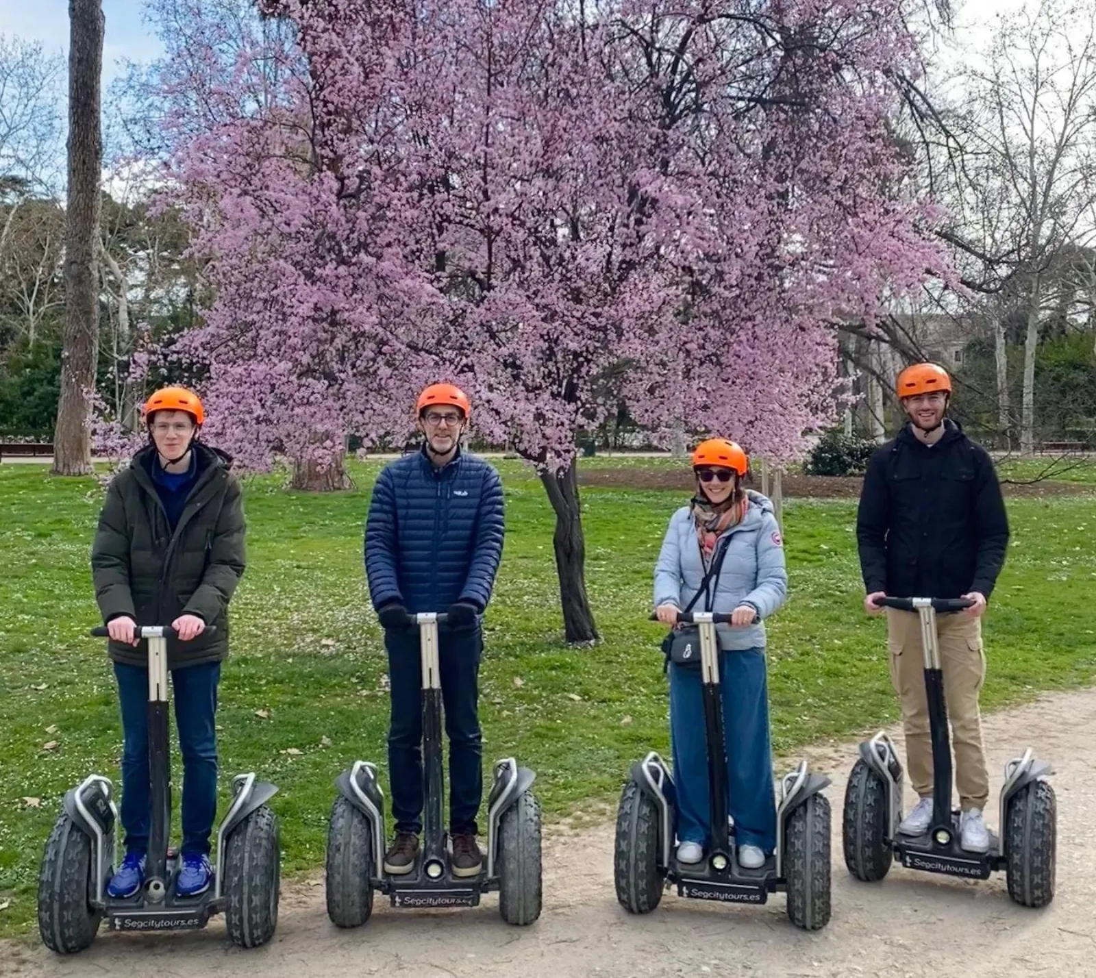 Riders on all-terrain Segways under spring blossom in Retiro Park