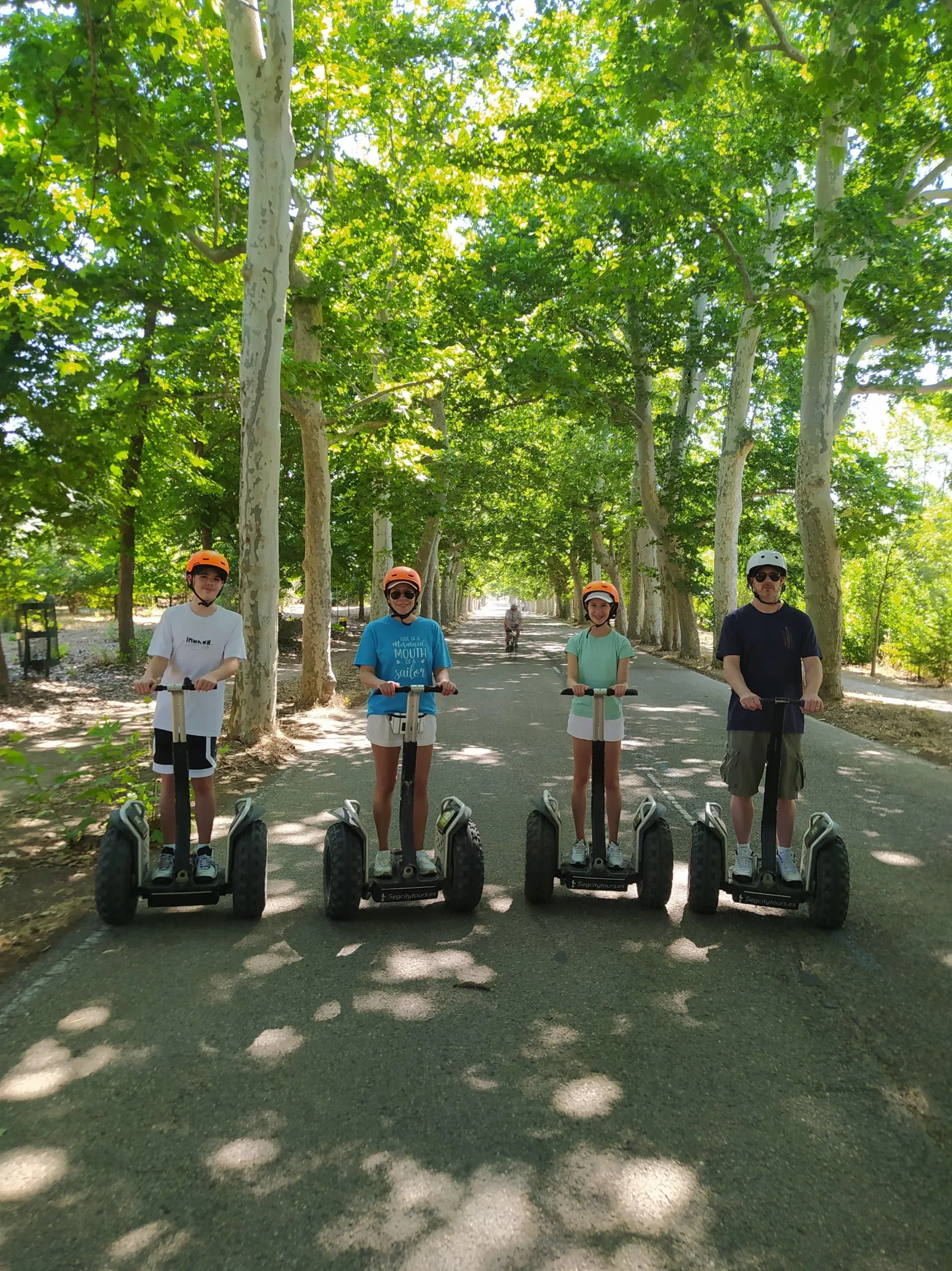 Three riders on Segways on a tree-lined path in Casa de Campo